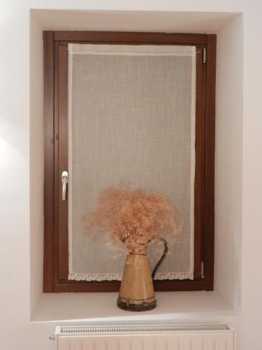 a vase with flowers sitting on a shelf in a window at Casa de la Cadena in Asiáin