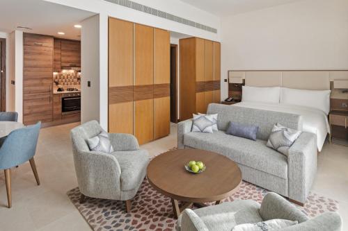 a living room with a bed and a couch and chairs at Staybridge Suites Dubai Al-Maktoum Airport by IHG in Dubai