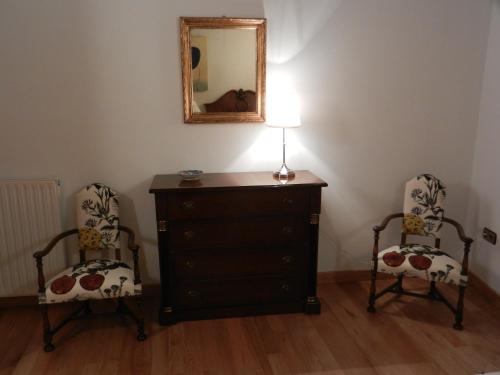 a bedroom with two chairs and a dresser with a mirror at Casa de la Cadena in Asiáin