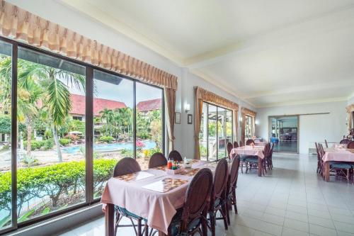 a restaurant with tables and chairs and large windows at Ban Nam Mao Resort in Na Jomtien