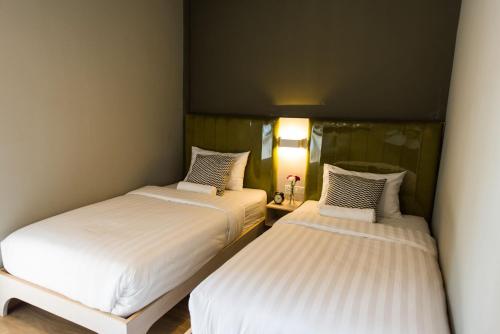 two twin beds in a room with a mirror at V Varee Bangkok in Bangkok