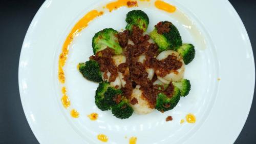 a white plate of food with broccoli and sauce at V Varee Bangkok in Bangkok