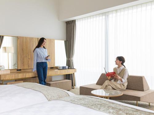 a woman is standing in a hotel room at Garden Terrace Saga Hotel & Resorts in Saga