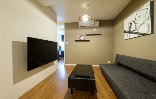 a living room with a couch and a flat screen tv at Shiki Homes KURUMI in Osaka