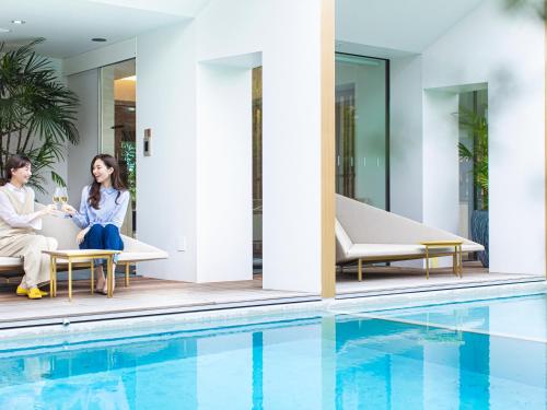 a man and woman sitting on chairs next to a swimming pool at Garden Terrace Saga Hotel & Resorts in Saga