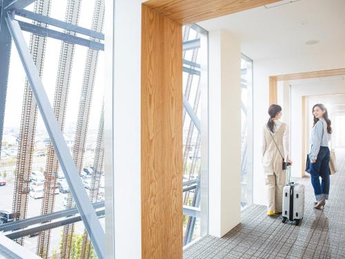 two women standing in a hallway with luggage looking out the window at Garden Terrace Saga Hotel & Resorts in Saga