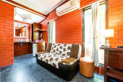 Tom Pizza Resort في كو ساميد: غرفة معيشة مع أريكة في جدار من الطوب الأحمر
