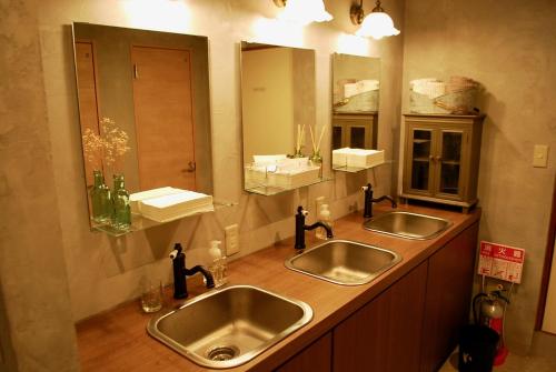 a bathroom with two sinks and two mirrors at Nawate Guesthouse in Matsumoto