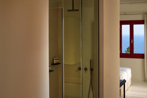 a bathroom with a shower with a glass door at Potnia Theron Suites in Akrotiri