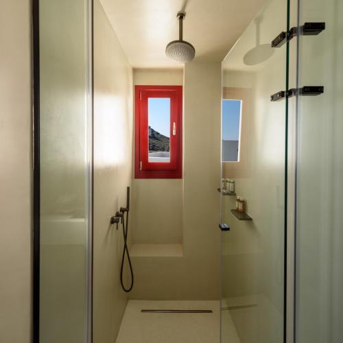 a bathroom with a shower with a red window at Potnia Theron Suites in Akrotiri