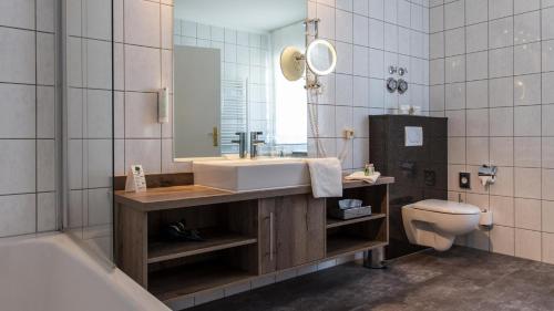 ein Badezimmer mit einem Waschbecken, einem WC und einem Spiegel in der Unterkunft Romantik Hotel Schubert in Lauterbach