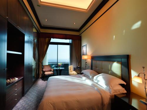 a bedroom with a large bed with a large window at Raouche Arjaan by Rotana in Beirut