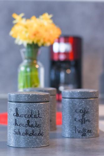 three metal containers sitting on a table with a vase of flowers at Appartement "le Terminus " Gare-Cosy-Wifi 6 Personnes in Saint-Quentin