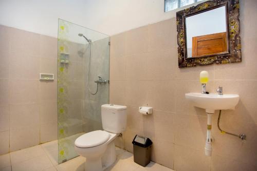 a bathroom with a toilet and a sink and a shower at The Puncak Santhi Inn in Nusa Penida