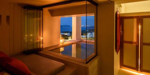 a room with a balcony with a view of a pool at Potnia Theron Suites in Akrotiri