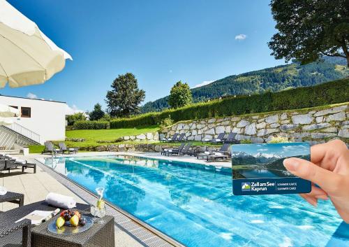 una persona con una tarjeta junto a una piscina en Das Alpenhaus Kaprun inkl Zell am See-Kaprun Sommerkarte en Kaprun