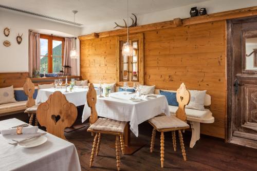 a restaurant with white tables and chairs and wooden walls at Berghotel Rehlegg in Ramsau