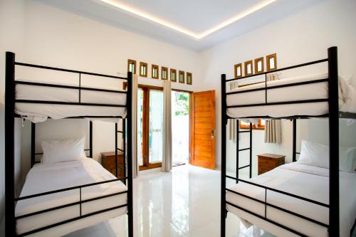 2 letti a castello in una camera con pareti bianche di The Puncak Santhi Inn a Nusa Penida