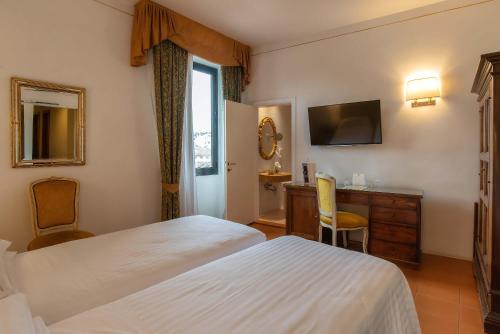a hotel room with two beds and a desk at Hotel Machiavelli Palace in Florence