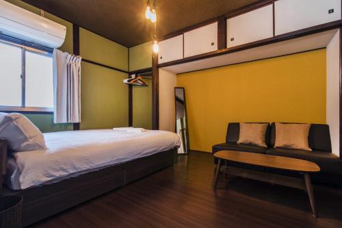 a bedroom with a bed and a chair and a table at Shiki Homes KURIKO in Osaka