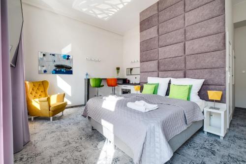 a bedroom with a large bed and a yellow chair at SAVOY Mariacka Apartments in Katowice