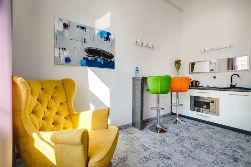 a living room with a yellow chair and a kitchen at SAVOY Mariacka Apartments in Katowice