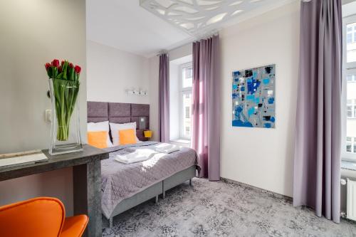 a bedroom with a bed and a vase of flowers at SAVOY Mariacka Apartments in Katowice