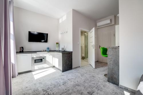 a kitchen with white cabinets and a tv on the wall at SAVOY Mariacka Apartments in Katowice
