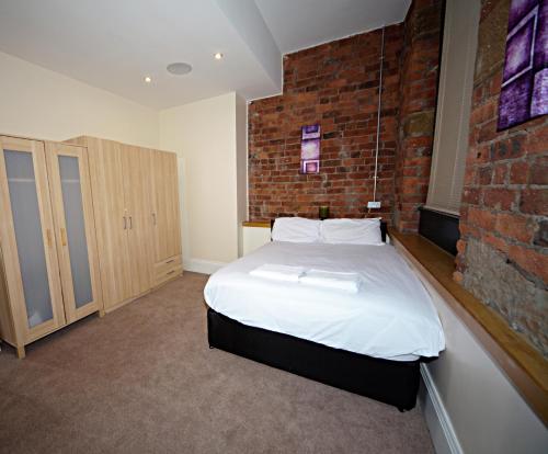 a bedroom with a bed and a brick wall at Premier Apartments in Bradford