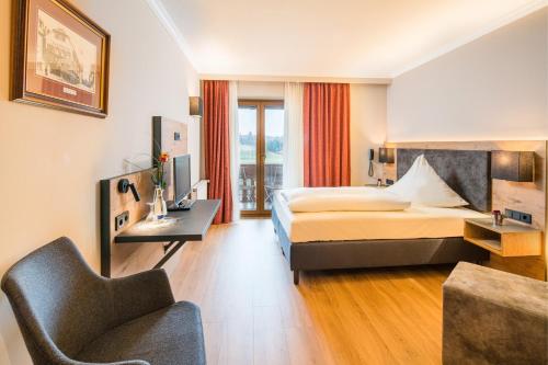een hotelkamer met een bed en een stoel bij Hotel-Gasthof Huber in Ebersberg