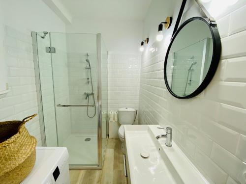 een witte badkamer met een wastafel en een spiegel bij "MER" Séjour détente tout confort, magnifique vue sur la mer in Canet-en-Roussillon