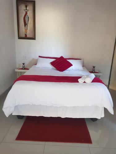 a bedroom with a large white bed with red sheets at ONNIE GUESTHOUSE in Louis Trichardt