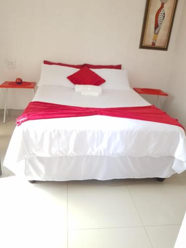 a large white bed with a red blanket on it at ONNIE GUESTHOUSE in Louis Trichardt