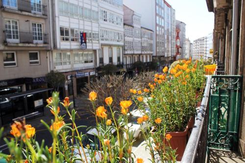balkon z pomarańczowymi kwiatami na ulicy miejskiej w obiekcie Hotel Hórreo by Bossh! Hotels w Santiago de Compostela