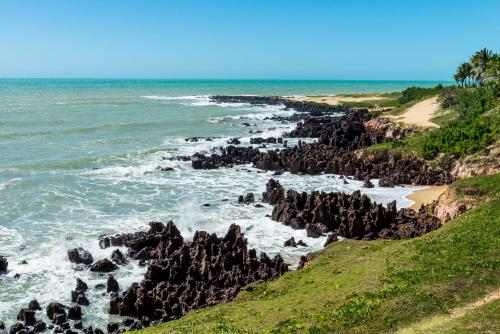 a view of a beach with rocks in the ocean at Hotel Senac Barreira Roxa in Natal