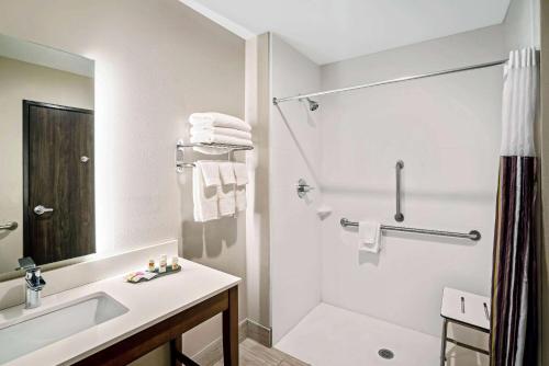 uma casa de banho branca com um lavatório e um chuveiro em La Quinta by Wyndham Tuscaloosa McFarland em Tuscaloosa