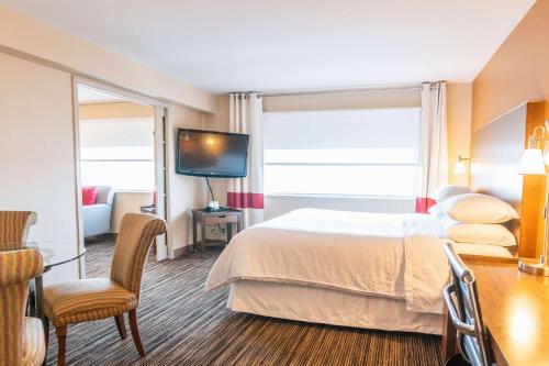 a hotel room with a bed and a flat screen tv at Lakeview Signature, Trademark Collection by Wyndham in Winnipeg