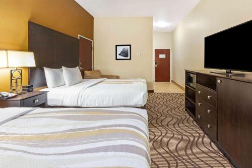 a hotel room with two beds and a flat screen tv at La Quinta by Wyndham South Bend in South Bend
