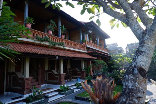 a building with potted plants on the balcony of it at Danasari Homestay in Ubud