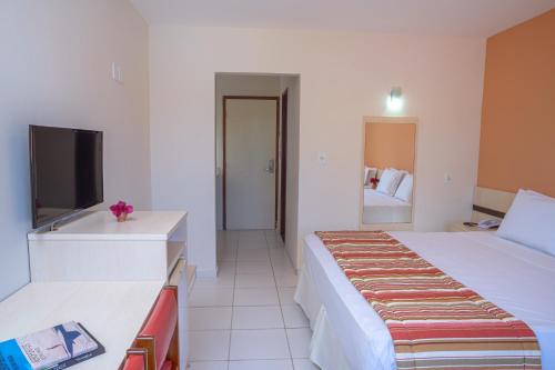 um quarto de hotel com uma cama e uma televisão em Portobello Park Hotel em Porto Seguro