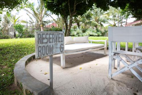 a sign sitting next to a white couch and a chair at Kobe Suite Resort in Watamu