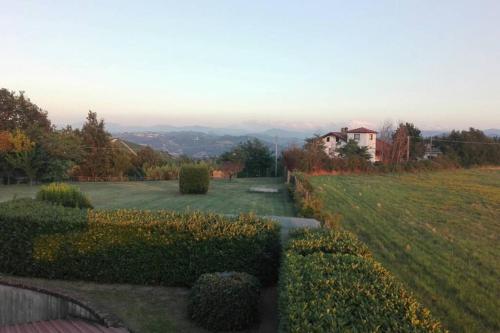 a view of a garden with a house in the distance at Alloggio nella Villa dell'Edera in Acqui Terme