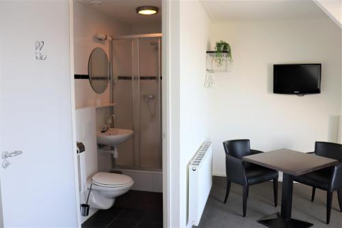 een badkamer met een toilet, een tafel en een wastafel bij Stadsherberg 'Het Wapen van IJlst' in IJlst