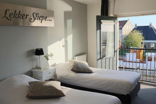 a bedroom with two beds and a window with a balcony at Stadsherberg 'Het Wapen van IJlst' in IJlst