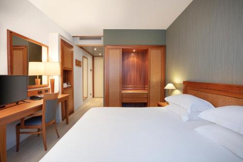 a bedroom with a bed and a desk and a television at Crowne Plaza Milan Linate by IHG in San Donato Milanese