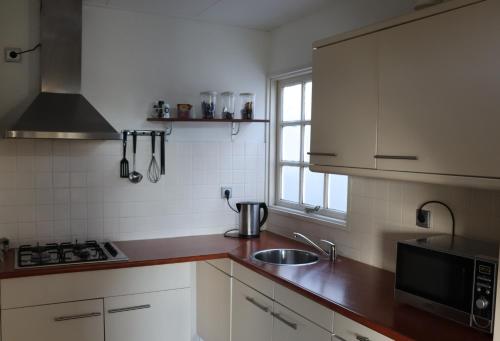 a kitchen with white cabinets and a sink and a microwave at Stadsherberg 'Het Wapen van IJlst' in IJlst