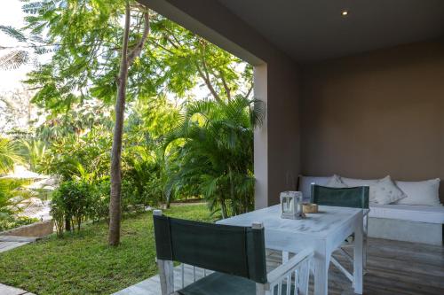 a white table and chairs with a couch and trees at Kobe Suite Resort in Watamu