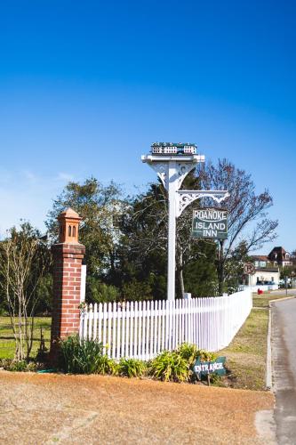 a white fence with a street sign in front of a white picket fence at Roanoke Island Inn in Manteo