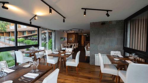 a restaurant with wooden tables and white chairs at Hotel Alto Traful in Villa Traful
