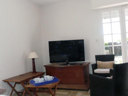 a living room with a flat screen tv and a chair at LE PHARE - Maison Riantec, Plage 130m - PL6003 in Riantec